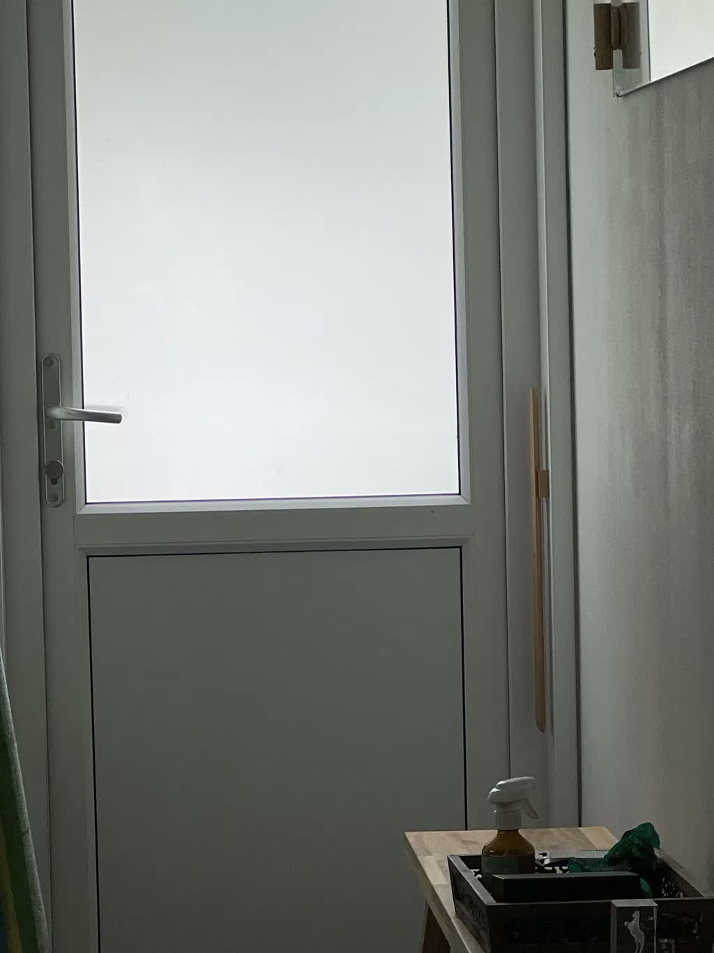 Skohorn i naturlig bøg på gråbeige væg ved siden af hvid havedør med matteret glas