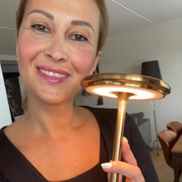 Kunde holder Copenhagen bordlampe i guld op foran sig